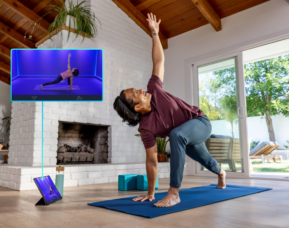 Man in his living room following a yoga workout on his tablet