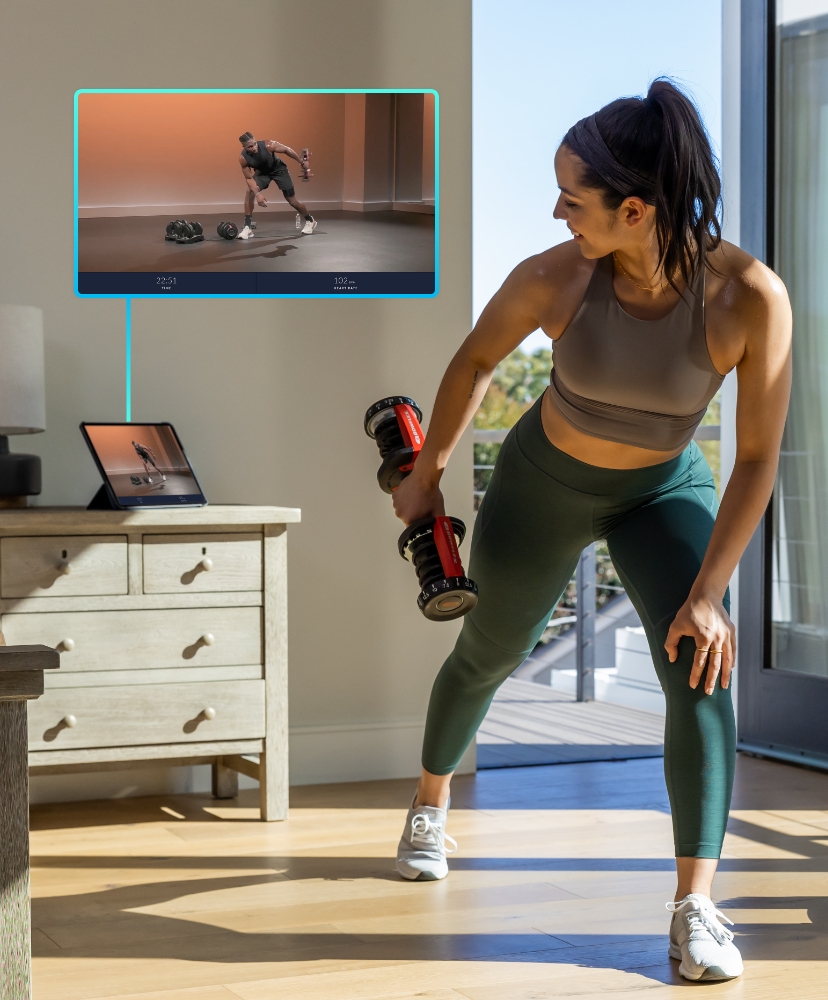 Woman following a JRNY dumbbell workout on a tablet