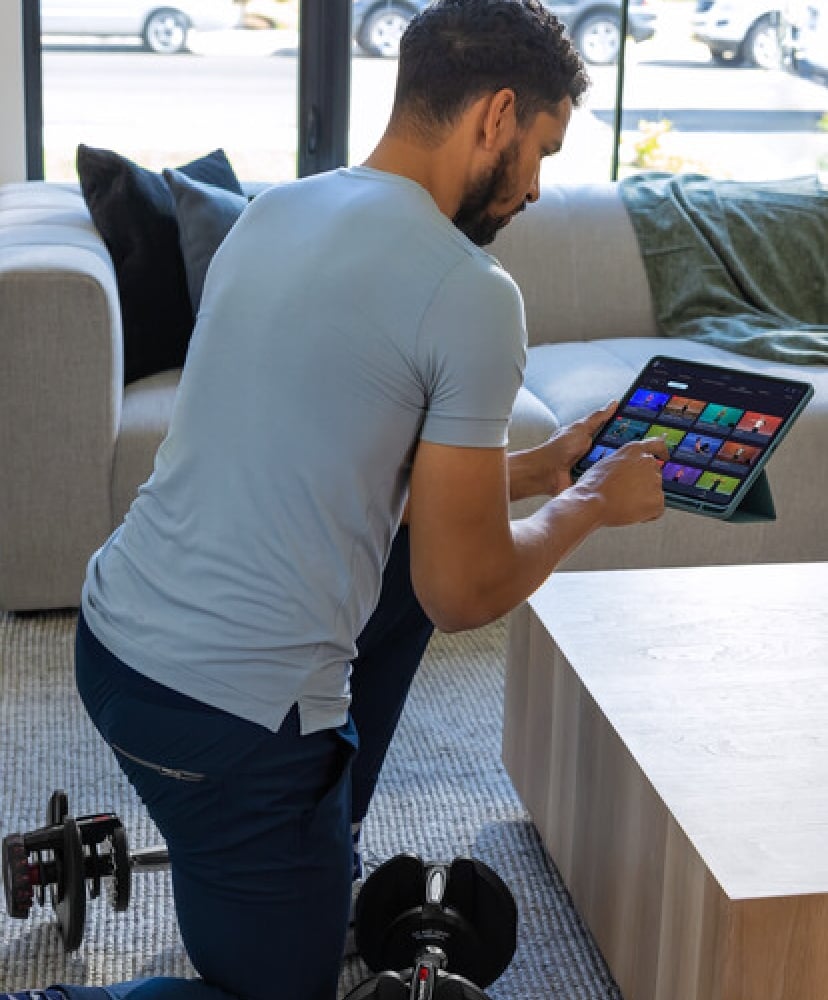 Man selecting a JRNY dumbbell workout on a tablet